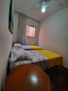 two twin beds in a room with a window at Yellow Hostel Praia da Costa in Vila Velha
