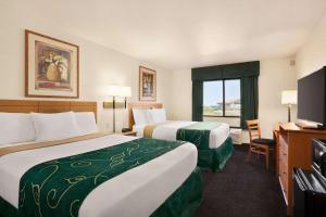 a hotel room with two beds and a television at Travelodge by Wyndham Pecos in Pecos