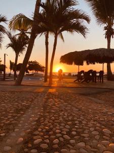 una playa con palmeras y una persona sentada en un banco en Hotel Al Mare en Santa Cruz de Barahona