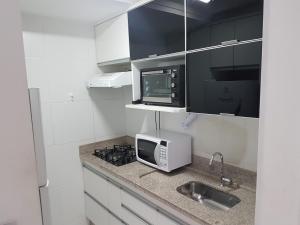 La cuisine est équipée d'un four micro-ondes et d'un évier. dans l'établissement Flat mobiliado em região nobre de Goiânia, à Goiânia