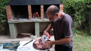 a man preparing a turkey in front of a brick oven at posada cerro los nogales in San Agustín de Valle Fértil