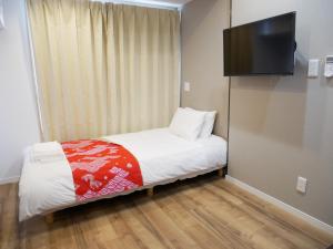 Habitación pequeña con cama y TV de pantalla plana. en Tokyo shinjukutei Hotel Asahi gruop 東京新宿亭ホテル en Tokio