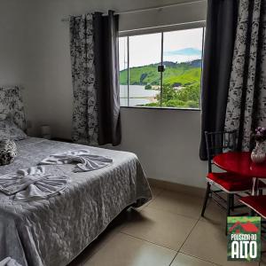 een slaapkamer met een bed en een groot raam bij Pousada Do Alto in Capitólio