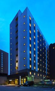 a large building with windows in a parking lot at Smile Hotel Utsunomiya Nishiguchi Ekimae in Utsunomiya