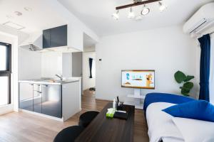Una sala de estar con un sofá azul y una cocina. en Grand Inn Canalside, en Fukuoka