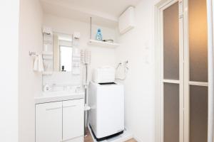 a white kitchen with a refrigerator and a sink at Grand Inn Canalside in Fukuoka