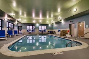 a pool in a large room with chairs and tables at Holiday Inn Express Hotel & Suites Morris by IHG in Morris