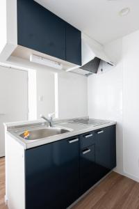 a kitchen with black and white cabinets and a sink at Grand Inn Canalside in Fukuoka