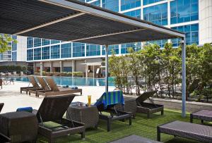a patio area with chairs, tables and umbrellas at Orchard Hotel Singapore in Singapore