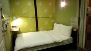 Cama pequeña en habitación con paredes verdes en Decordo Hostel, en Bangkok