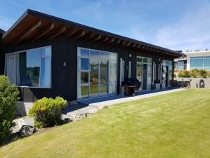 a black house with a lawn in front of it at Three Rivers Lodge in Lake Tekapo