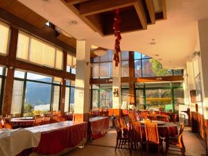 a dining room with tables and chairs and windows at Cloud Falls Resort in Ren'ai