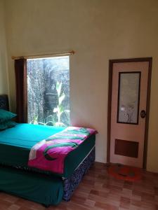 a bedroom with a bed with a window at Nita's Homestay Banyuwangi in Banyuwangi