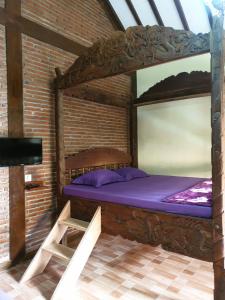 a bedroom with a wooden bed in a brick wall at Nita's Homestay Banyuwangi in Banyuwangi