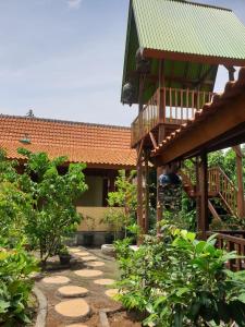 a garden with a building with a deck and a staircase at Nita's Homestay Banyuwangi in Banyuwangi