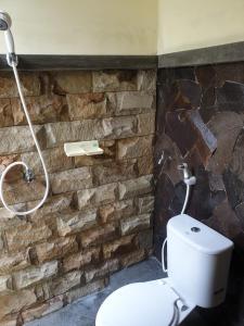 a bathroom with a toilet and a stone wall at Nita's Homestay Banyuwangi in Banyuwangi