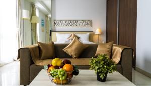 a living room with a couch and a bowl of fruit at Azalea Suites Cikarang by Jayakarta Group in Bekasi
