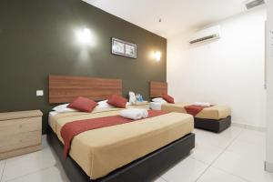 1 Schlafzimmer mit 2 Betten und einer grünen Wand in der Unterkunft COOP HOTEL PUTRAJAYA & CYBERJAYA in Kampung Dengkil