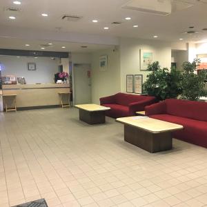 a waiting room with red couches and tables in a lobby at Hotel Tetora Makuhari Inagekaigan (Formerly Business Hotel Marine) in Chiba