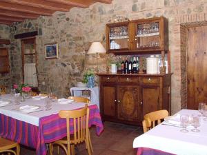 a dining room with tables and chairs and a stone wall at Les Velles Escoles in Les Irles