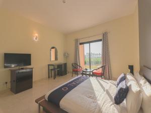 CAPITAL O133 Al Sawadi Beach Resort & Spa في بركاء: غرفة نوم بسرير كبير وتلفزيون