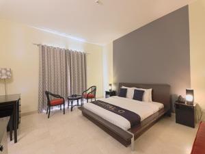 CAPITAL O133 Al Sawadi Beach Resort & Spa في بركاء: غرفة نوم بسرير ومكتب وكراسي