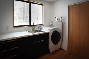 a kitchen with a washing machine and a sink at Akamatsu House in Hakuba +61 photos