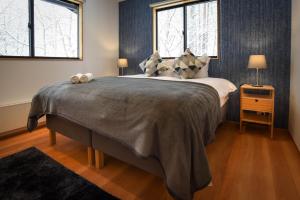 a bedroom with a large bed and two windows at Akamatsu House in Hakuba