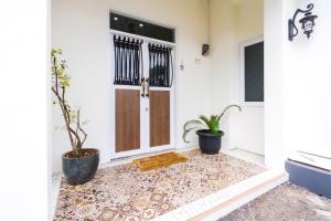 a door with two potted plants in front of it at OYO 2975 House Of Mahira Syariah in Ciamis