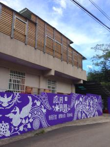 a building with a purple wall with drawings on it at Shuitianfarm in Jianshi