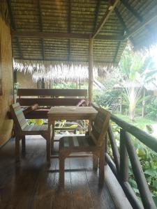 a table and chairs on a porch with a bench at Jungle Garden in Ko Chang