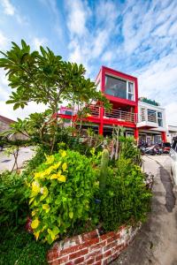 una casa roja con un árbol y algunas plantas en Mahalo B&B, en Magong