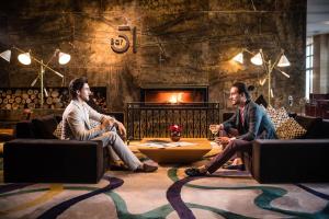 two men sitting on couches in a living room with a fireplace at Sheraton Baku Intourist in Baku