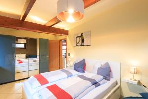 Un dormitorio con una cama blanca con almohadas azules y rojas en Ferienwohnung Isabella am Möhnesee, en Möhnesee
