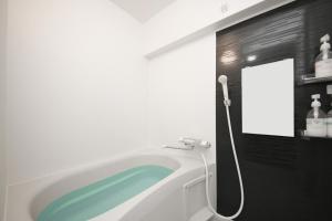 uma banheira na casa de banho com um espelho em goom Hotel Hakata-Higashihie-Ekimae em Fukuoka