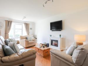 a living room with two couches and a fireplace at Y Gyfrinach in Morfa Nefyn