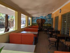 un restaurant avec des tables et des chaises et une fresque murale représentant un éléphant dans l'établissement Kambua Resort, à Libwezi