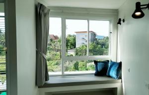 a window with two pillows sitting on a window sill at beHOME Phuket in Nai Yang Beach