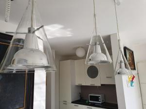 eine Küche mit drei Lichtern, die von der Decke hängen in der Unterkunft Il Parco 2 by Quokka 360 - cosy flat with terrace in Lugano