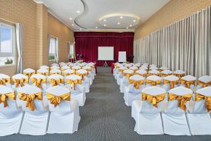 Cette chambre comprend des rangées de tables et de chaises blanches avec des archets jaunes. dans l'établissement Nesta Hotel Can Tho, à Cần Thơ