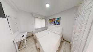 a white bedroom with a bed and a desk at Apartamentos Design Pinemar in Cabañas