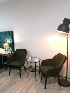 2 chaises, une table et une lampe dans une pièce dans l'établissement Apartamenty Lawendowy Zakątek 2, à Carolinensiel