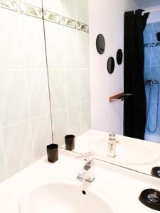 La salle de bains blanche est pourvue d'un lavabo et d'un miroir. dans l'établissement Bleu du Sud, au Cap d'Agde