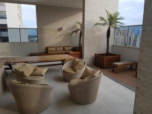 a living room with chairs and a table and a palm tree at Flat mobiliado em região nobre de Goiânia in Goiânia