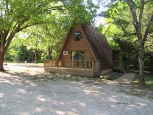 a small house with a porch and a clock on it at Bar M Resort & Campground in Branson West +7 photos