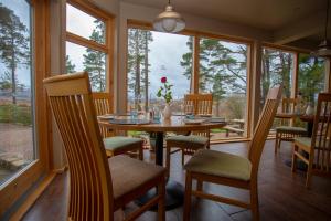 a dining room with a table and chairs and windows at Old Pines Hotel And Restaurant in Spean Bridge