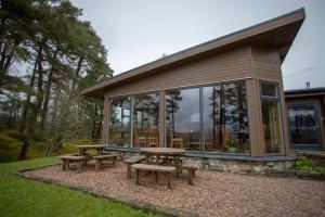 una mesa de picnic y bancos frente a una casa en Old Pines Hotel And Restaurant, en Spean Bridge