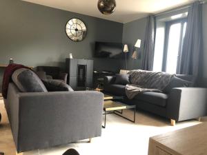 a living room with two couches and a clock on the wall at Maison de Pauline, Chablis Vineyard in Préhy