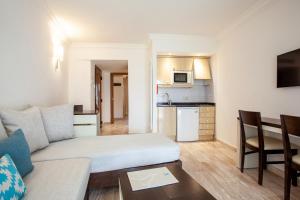 a living room with a couch and a kitchen at Grupotel Los Príncipes & Spa in Playa de Muro