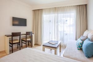 a living room with a couch and a table in a room at Grupotel Los Príncipes & Spa in Playa de Muro